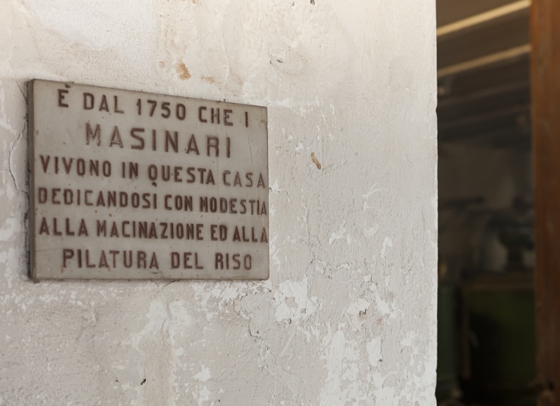 Targa commemorativa all'ingresso della riseria Masinari riportante il testo "E' dal 1750 che i Masinari vivono in questa casa dedicandosi con modestia alla macinazione ed alla pilatura del riso".